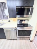 Kitchen with stainless steel appliances, light countertops, and light wood finished floors - 