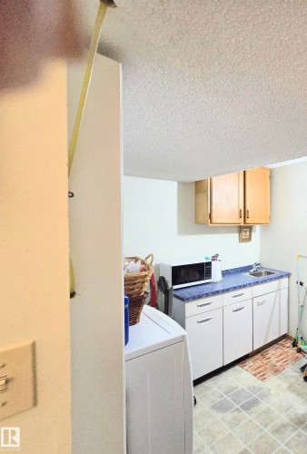 Laundry area with a textured ceiling and washer / clothes dryer - 2 4403 Riverbend Road, Edmonton, AB - Indoor