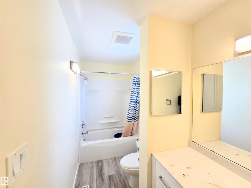 Bathroom featuring vanity, shower / tub combo with curtain, and light wood finished floors - 2 4403 Riverbend Road, Edmonton, AB - Indoor Photo Showing Bathroom