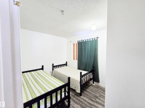 Bedroom featuring a textured ceiling and dark wood finished floors - 2 4403 Riverbend Road, Edmonton, AB - Indoor