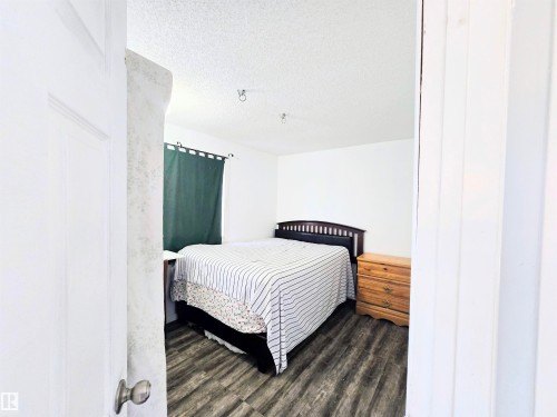 Bedroom featuring a textured ceiling and dark wood finished floors - 2 4403 Riverbend Road, Edmonton, AB - Indoor Photo Showing Bedroom