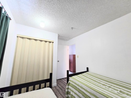 Bedroom with a textured ceiling, a closet, and dark wood-style flooring - 2 4403 Riverbend Road, Edmonton, AB - Indoor Photo Showing Bedroom