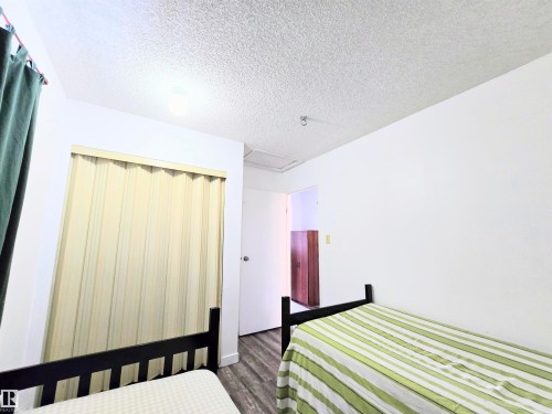 Bedroom with a textured ceiling, a closet, and dark wood finished floors - 2 4403 Riverbend Road, Edmonton, AB - Indoor Photo Showing Bedroom