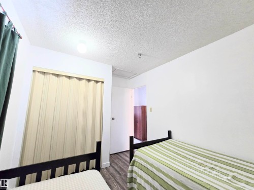 Bedroom featuring a textured ceiling, a closet, and dark wood-type flooring - 2 4403 Riverbend Road, Edmonton, AB - Indoor Photo Showing Bedroom