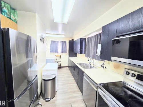 Kitchen with stainless steel appliances, light countertops, and dark cabinetry - 2 4403 Riverbend Road, Edmonton, AB - Indoor Photo Showing Kitchen With Double Sink
