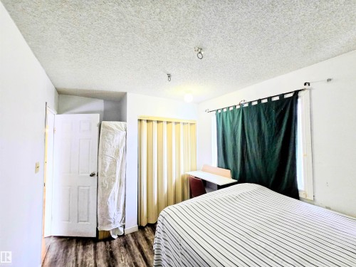 Bedroom with a textured ceiling and dark wood-style floors - 2 4403 Riverbend Road, Edmonton, AB - Indoor Photo Showing Bedroom