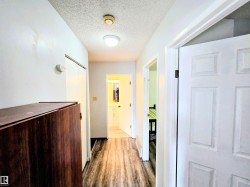 Corridor with a textured ceiling and dark wood-type flooring - 