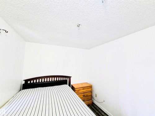 Bedroom with a textured ceiling and dark wood-style floors - 2 4403 Riverbend Road, Edmonton, AB - Indoor Photo Showing Bedroom