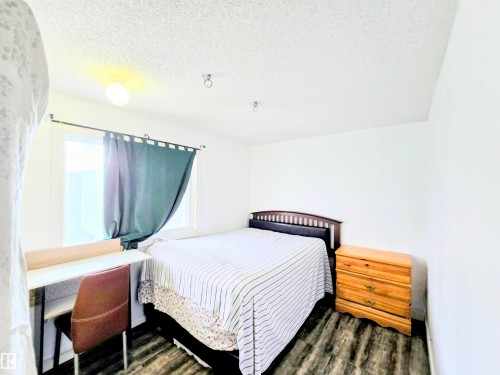 Bedroom with a textured ceiling and dark wood-style flooring - 2 4403 Riverbend Road, Edmonton, AB - Indoor Photo Showing Bedroom