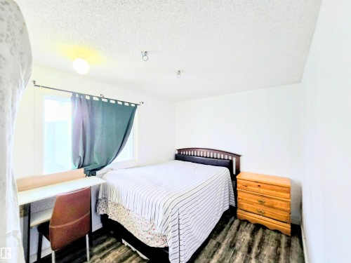 Bedroom featuring a textured ceiling and dark wood-style flooring - 2 4403 Riverbend Road, Edmonton, AB - Indoor Photo Showing Bedroom