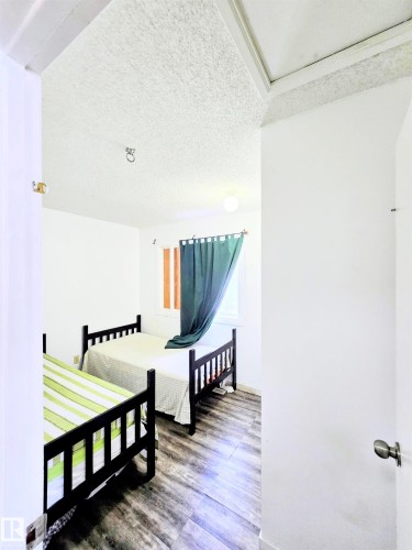 Bedroom with a textured ceiling and wood finished floors - 2 4403 Riverbend Road, Edmonton, AB - Indoor