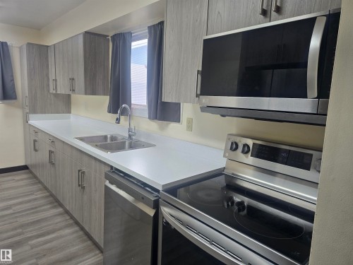 Kitchen featuring extensive gray wood-finish cabinetry, bright white countertops, and wood-finish flooring - 2 4403 Riverbend Road, Edmonton, AB 