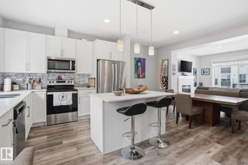 Kitchen featuring stainless steel appliances, open floor plan, a kitchen island, a breakfast bar, and white cabinets - 90 1010 Rabbit Hill Road, Edmonton, AB - Indoor Photo Showing Kitchen With Stainless Steel Kitchen With Upgraded Kitchen