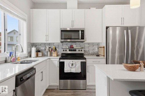 Kitchen featuring stainless steel appliances, light stone counters, white cabinets, light wood-style floors, and tasteful backsplash - 90 1010 Rabbit Hill Road, Edmonton, AB - Indoor Photo Showing Kitchen With Stainless Steel Kitchen With Double Sink With Upgraded Kitchen