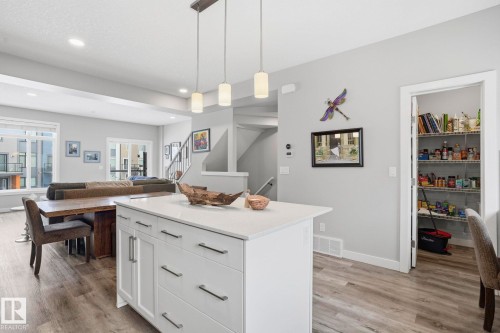 Kitchen featuring white cabinets, hanging light fixtures, a kitchen island, light wood-style floors, and open floor plan - 90 1010 Rabbit Hill Road, Edmonton, AB - Indoor