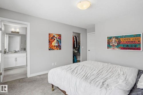 Bedroom with light carpet, a walk in closet, and ensuite bath - 90 1010 Rabbit Hill Road, Edmonton, AB - Indoor Photo Showing Bedroom