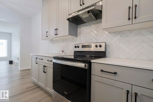 Kitchen featuring electric range, light wood-style floors, backsplash, and light stone counters - 3520 Kulay Link Link, Edmonton, AB - Indoor Photo Showing Kitchen With Upgraded Kitchen