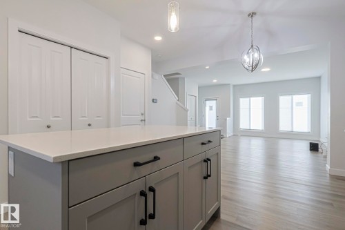Kitchen with gray cabinetry, a center island, a chandelier, light wood-type flooring, and open floor plan - 3520 Kulay Link Link, Edmonton, AB - Indoor Photo Showing Other Room