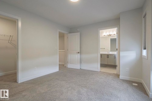 Unfurnished bedroom with a walk in closet, light colored carpet, and ensuite bathroom - 3520 Kulay Link Link, Edmonton, AB - Indoor