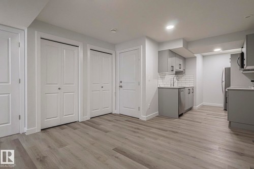 Dual tone kitchen with decorative backsplash, light wood-type flooring, stainless steel appliances, light countertops, and two tone color scheme - 3520 Kulay Link Link, Edmonton, AB - Indoor Photo Showing Kitchen