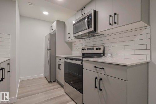 Kitchen with stainless steel appliances, light wood finished floors, gray cabinetry, recessed lighting, and decorative backsplash - 3520 Kulay Link Link, Edmonton, AB - Indoor Photo Showing Kitchen