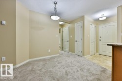 Carpeted living area with neutral-toned walls, featuring a pendant light fixture and white baseboards - 