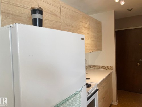 Kitchen featuring white appliances, light countertops, and light wood finish cabinetry - 205 10345 123 Street, Edmonton, AB - Indoor Photo Showing Kitchen