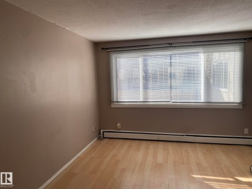 Spare room featuring a baseboard heating unit, a textured ceiling, and light wood-type flooring - 205 10345 123 Street, Edmonton, AB - Indoor Photo Showing Other Room