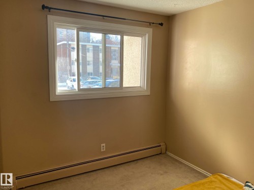 Unfurnished room featuring baseboard heating, light carpet, and a textured ceiling - 205 10345 123 Street, Edmonton, AB - Indoor Photo Showing Other Room