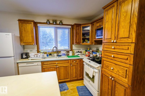 Kitchen with white appliances, wood finish cabinets, and light countertops - 4812 51 Avenue, Vilna, AB - Indoor Photo Showing Kitchen