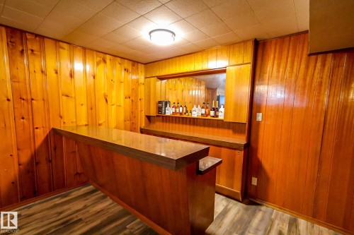 Indoor dry bar featuring dark wood-style flooring, dark countertops, wood finish cabinets, and wood walls - 4812 51 Avenue, Vilna, AB - Indoor Photo Showing Other Room