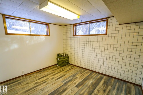 Basement with dark wood-type flooring, plenty of natural light, and an accent wall - 4812 51 Avenue, Vilna, AB - Indoor