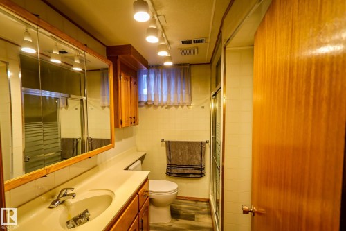 Bathroom with vanity, a stall shower, tile walls, dark wood-style floors, and rail lighting - 4812 51 Avenue, Vilna, AB - Indoor Photo Showing Bathroom