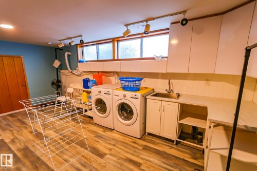 Laundry room featuring light wood-style floors, track lighting, washing machine and dryer, and cabinet space - 4812 51 Avenue, Vilna, AB - Indoor Photo Showing Laundry Room
