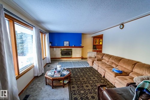 Living room with a textured ceiling, carpet, and a fireplace - 4812 51 Avenue, Vilna, AB - Indoor Photo Showing Living Room