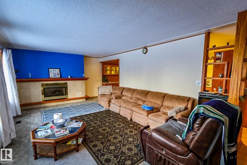 Carpeted living area featuring a textured ceiling and a tile fireplace - 4812 51 Avenue, Vilna, AB - Indoor Photo Showing Living Room