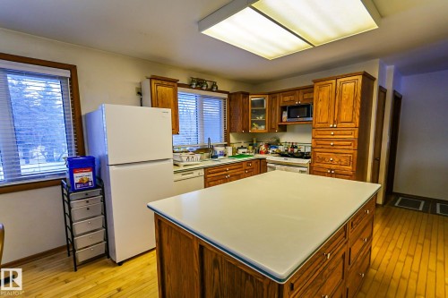 Kitchen featuring wood finish cabinets, white appliances, light countertops, and glass fronted cabinets - 4812 51 Avenue, Vilna, AB - Indoor Photo Showing Kitchen