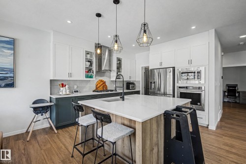 Kitchen with two tone color scheme, stainless steel appliances, an island with sink, a kitchen bar, and decorative backsplash - 34 Riverhill Crescent, St. Albert, AB - Indoor Photo Showing Kitchen With Upgraded Kitchen