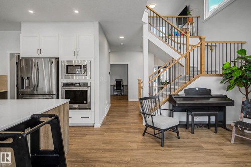 Kitchen featuring stainless steel appliances, light wood finished floors, light stone counters, recessed lighting, and dual tone cabinets - 34 Riverhill Crescent, St. Albert, AB - Indoor Photo Showing Other Room