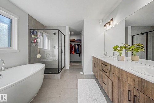 Bathroom featuring a stall shower, a freestanding bath, light tile patterned floors, a walk in closet, and double vanity - 34 Riverhill Crescent, St. Albert, AB - Indoor Photo Showing Bathroom