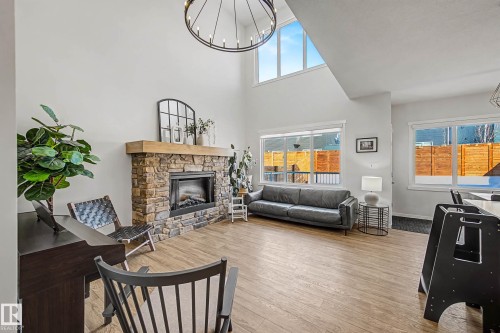 Living area with light wood-type flooring, a chandelier, a fireplace, and a high ceiling - 34 Riverhill Crescent, St. Albert, AB - Indoor Photo Showing Living Room With Fireplace