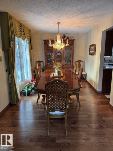 Dining area with suspended lighting, dark wood-type flooring, and a textured ceiling - 206 Wolf Willow Crescent, Edmonton, AB - Indoor Photo Showing Dining Room