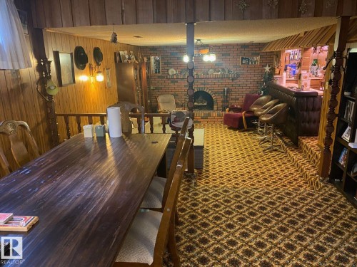 Dining space with wood walls, a brick fireplace, and brick wall - 206 Wolf Willow Crescent, Edmonton, AB - Indoor Photo Showing Dining Room