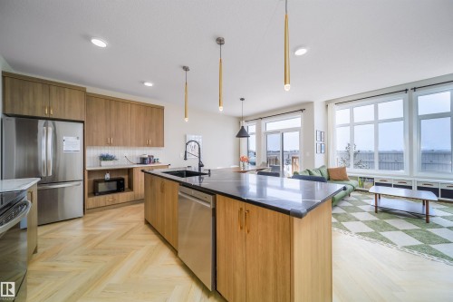 Kitchen featuring black appliances, parquet flooring, an island with sink, hanging light fixtures, and dark stone counters - 15 Chambery Crescent, St. Albert, AB - Indoor Photo Showing Kitchen With Upgraded Kitchen