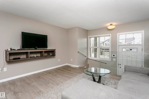 Living room featuring light wood-style flooring and a textured ceiling - 4011 Orchards Drive, Edmonton, AB - Indoor