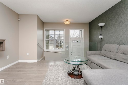 Living area featuring an accent wall, light wood-style floors, and wallpapered walls - 4011 Orchards Drive, Edmonton, AB - Indoor Photo Showing Living Room