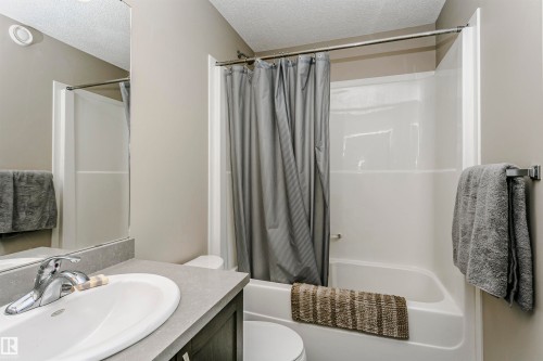 Bathroom featuring a textured ceiling, vanity, and shower / tub combo - 4011 Orchards Drive, Edmonton, AB - Indoor Photo Showing Bathroom