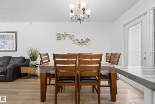 Dining room featuring a chandelier, light wood finished floors, and a textured ceiling - 17303 101 Street, Edmonton, AB - Indoor Photo Showing Dining Room