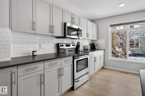 Kitchen featuring stainless steel appliances, light wood-type flooring, and a textured ceiling - 60 1804 70 Street, Edmonton, AB - Indoor Photo Showing Kitchen