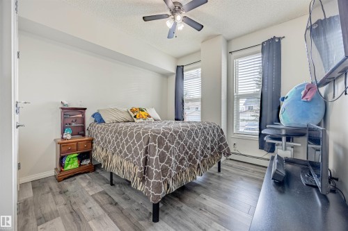Bedroom with wood finished floors, a textured ceiling, and a ceiling fan - 132 6220 134 Avenue, Edmonton, AB - Indoor Photo Showing Bedroom